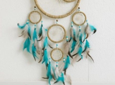 Dromenvanger met een grote bruine cirkel, een halve maan en kleinere cirkels; turquoise en bruine veren.