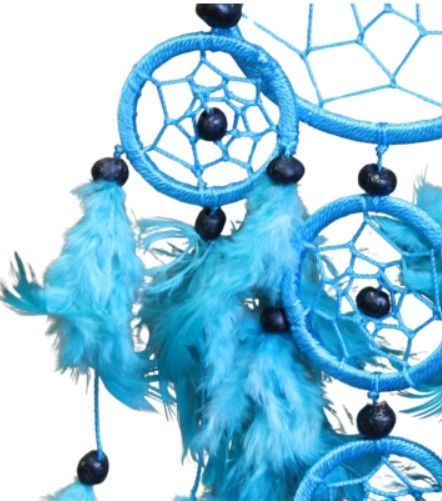 Turquoise dromenvanger aan een witte muur, versierd met meerdere geweven cirkels en veren.