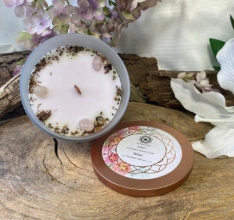 Een kaars in een blauw getint glazen potje met rozenkwartskristallen en een deksel met de tekst 