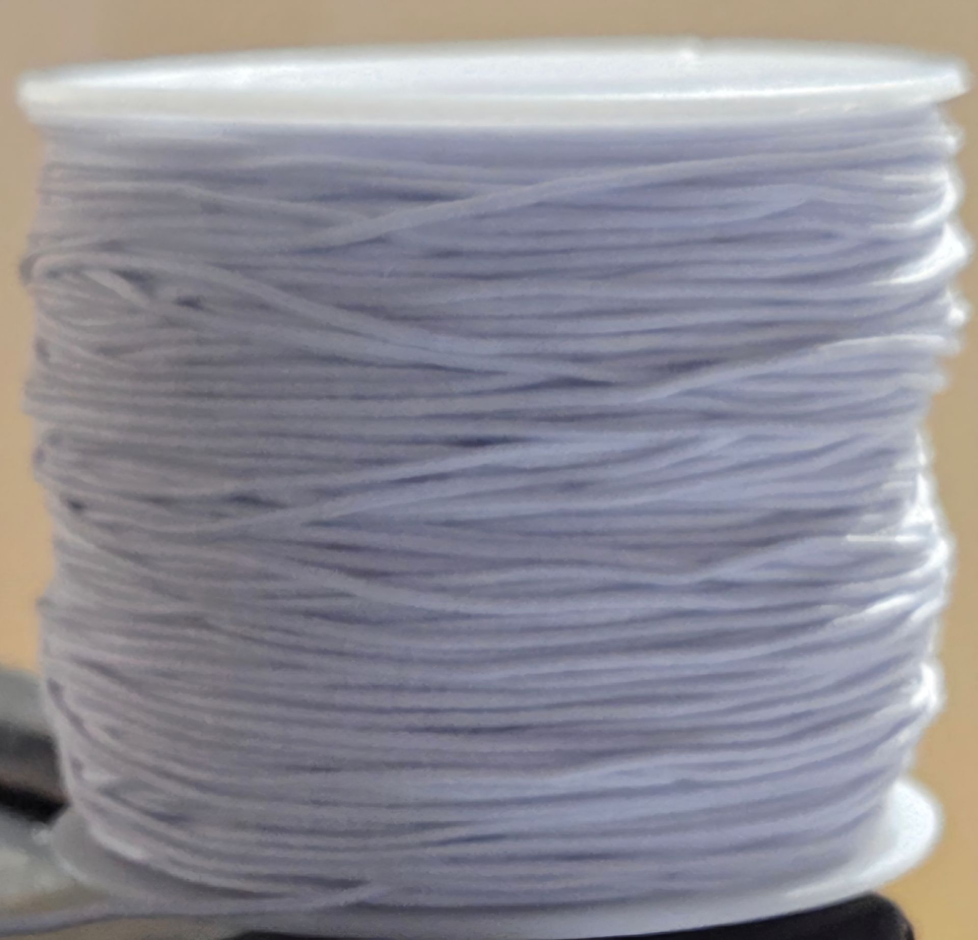 Spoel met lichtpaars elastisch koord, strak gewikkeld om een ​​witte kunststof kern.