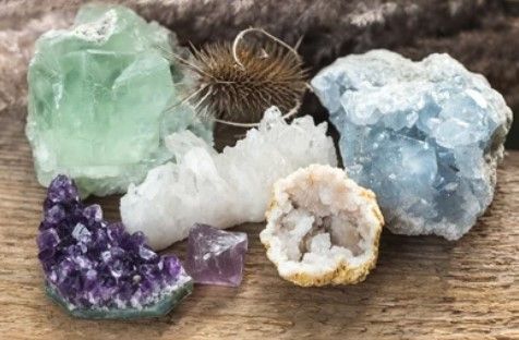 Verschillende kleurrijke kristallen: amethist, fluoriet, kwarts en celestien op een houten oppervlak.