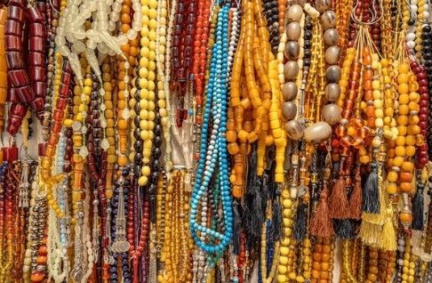 Rijen met kleurrijke gebedskralen: rood, geel, oranje, blauw, bruin en crème.