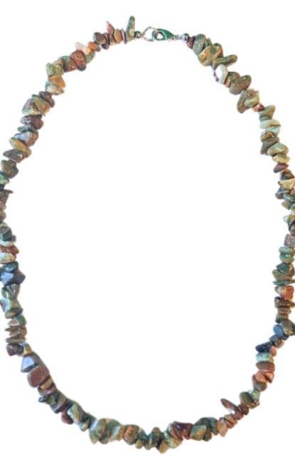 Ketting gemaakt van groene en bruine edelsteenstukjes op een houten ondergrond.