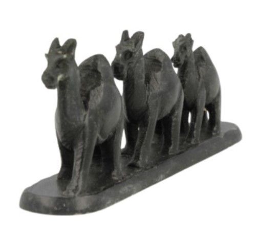 Drie donkere kamelen op een sokkel, naast elkaar, mogelijk een decoratiestuk.