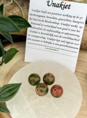 Vier ronde, ongepolijste kralen, roze en groen gespikkeld, met gaatjes erdoorheen geboord.