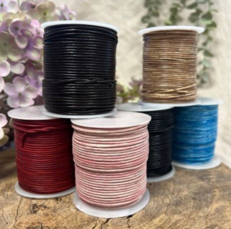 Een spoel van bruin en bruin touw op een houten oppervlak, met een zachte achtergrond van bloemen.