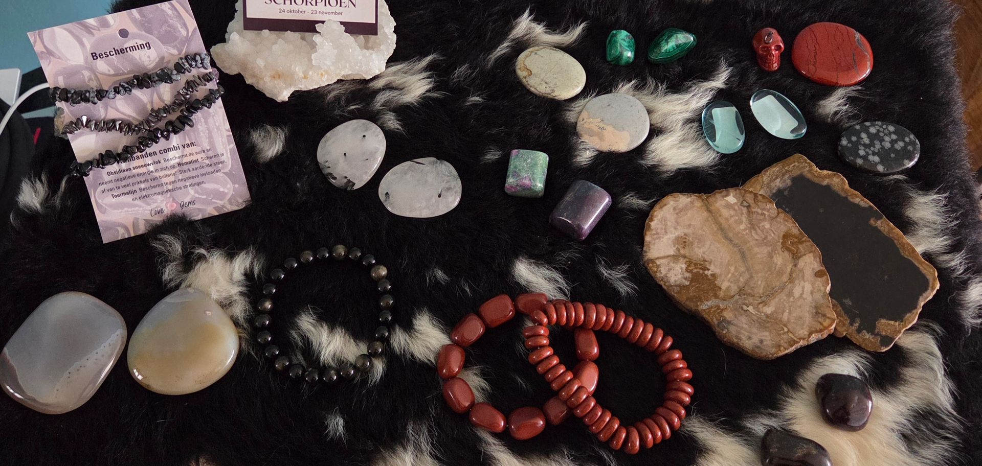 Diverse edelstenen en armbanden tentoongesteld op een zwart-wit patroon.