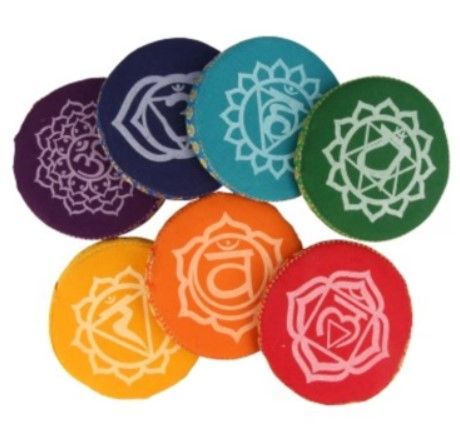 Kleurrijke chakra-meditatiekussens met gouden paisley-afwerking; het paarse bovenste kussen is voorzien van een Om-symbool.