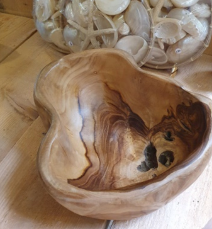 Houten kom met organische vorm, rustend op een houten oppervlak. Natuurlijke houtnerf met donkere en lichte vlakken.