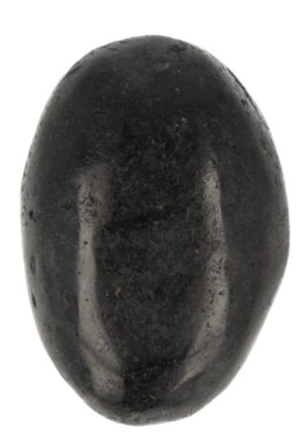 Hand die een zwarte steen vasthoudt boven een witte ronde schaal, met een andere zwarte steen zichtbaar en pluizig materiaal.