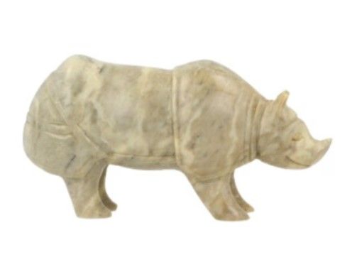 Gesneden beeld van een witte neushoorn, op een houten ondergrond, met groene bladranken op de achtergrond.