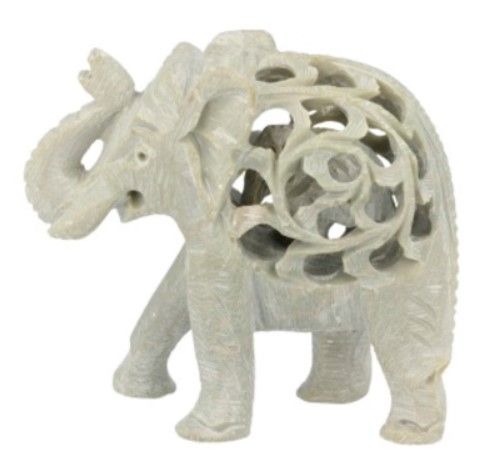 Wit gesneden olifantenbeeld op hout, met gesneden bloemendetails en groen op de achtergrond.