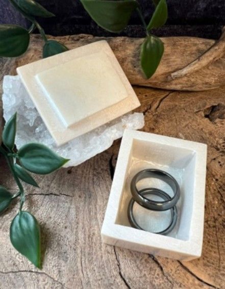 Gebroken witte, vierkante doos met het deksel een stukje open, waardoor een leeg interieur zichtbaar wordt.