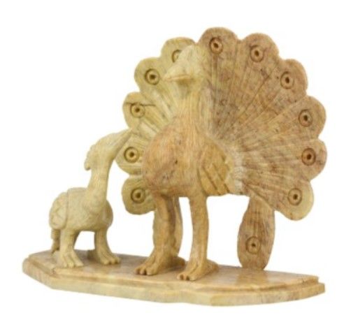 Een gebeeldhouwde, stenen pauw met zijn kuiken, lichtbeige, staand op een houten voetstuk.