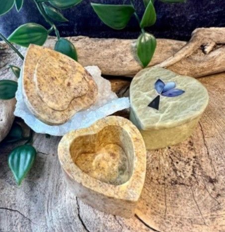 Hartvormig stenen doosje met open deksel, versierd met ingelegd vlindermotief; beige en roze.