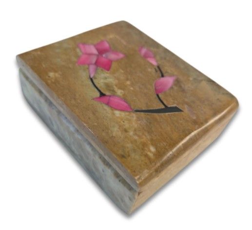 Drie stenen dozen met ingelegde bloemenmotieven op een houten oppervlak.