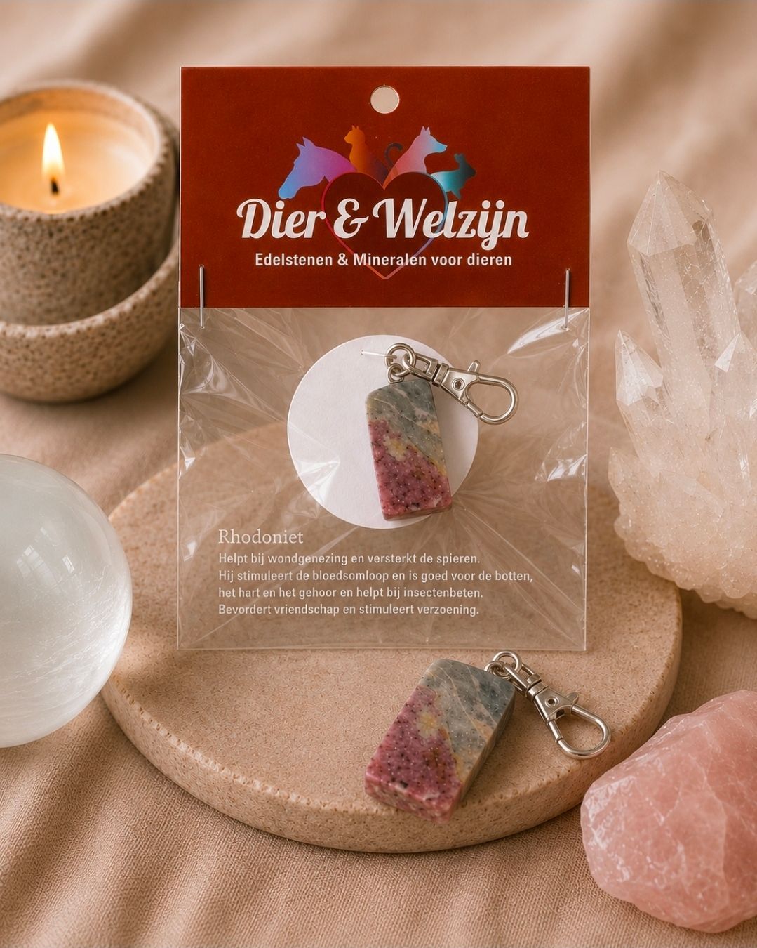Twee kristallen sleutelhangers op een beige kaartje naast kaarsen en rozenkwartskristallen.
