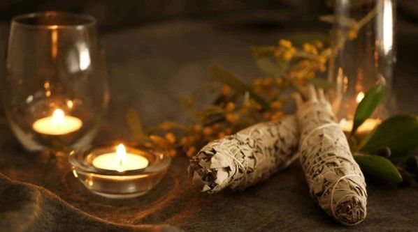 Kaarsen en saliebundels op doek, die een gevoel van sereniteit oproepen.