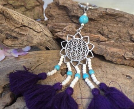 Sleutelhanger met zilveren bloem, blauwe kralen, witte kralen, paarse kwastjes.