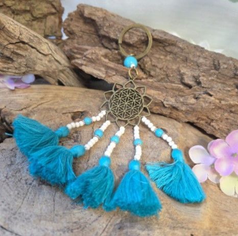 Turquoise sleutelhanger met kwastje, bronzen bloemenmotief en kralen.