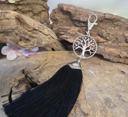 Zwarte sleutelhanger met kwastje en zilveren bedel van een levensboom.