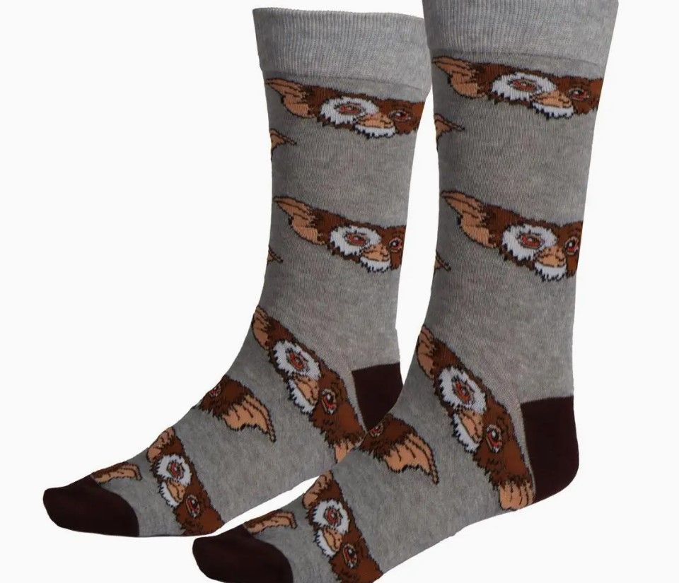 Gremlin-sokken. De sokken zijn grijs met bruine accenten en een herhalend patroon van Gremlin-gezichten.