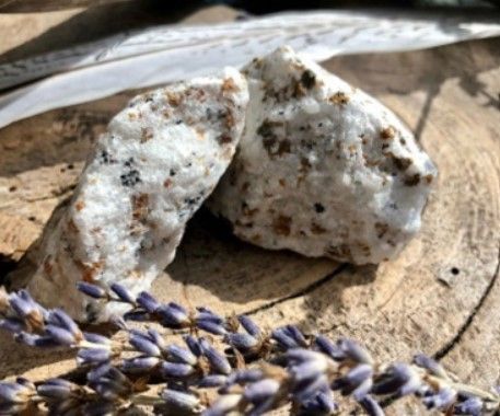 Wit gesteentemonster met bruine en zwarte vlekken in een klein kartonnen doosje.