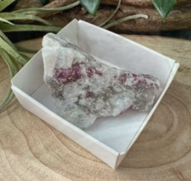 Een roze en wit toermalijnkristalmonster, gepresenteerd in een klein wit doosje.