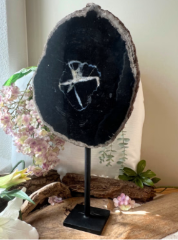 Een schijf van zwarte agaat op een zwarte metalen standaard, waarop de natuurlijke patronen van de steen te zien zijn.