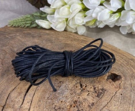 Een opgerold zwart touw, strak gebundeld, met een kleine lus in het midden en twee losse uiteinden die naar buiten uitsteken.