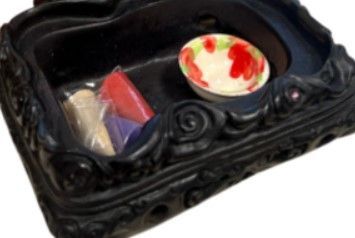 Beeld van een zwarte draak met een bol in zijn handen, op een decoratieve voet, op hout.