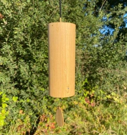 Windgong van hout, hangend aan een zwart koord, met een kleine, ronde houten klepel.