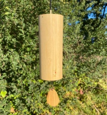 Windgong van hout met een cilindervormig lichaam en een druppelvormige klepel, hangend aan een koord.