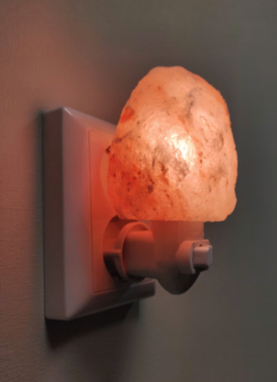 Roze Himalaya-zoutnachtlampje, aangesloten op een wit stopcontact.