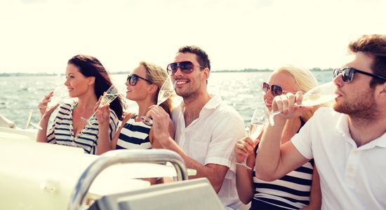 a group of people are sitting on a boat drinking wine .