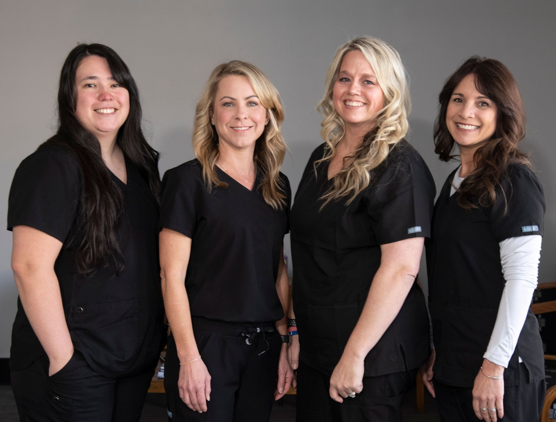 A group of women wearing black scrubs are posing for a picture.