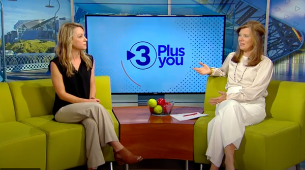 Two women are sitting on a couch in front of a television.