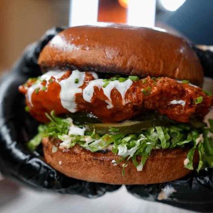 A person is holding a chicken sandwich in their hand.