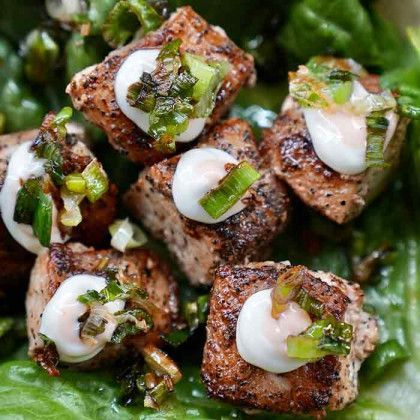 A close up of a plate of food with meat and vegetables on a lettuce leaf.
