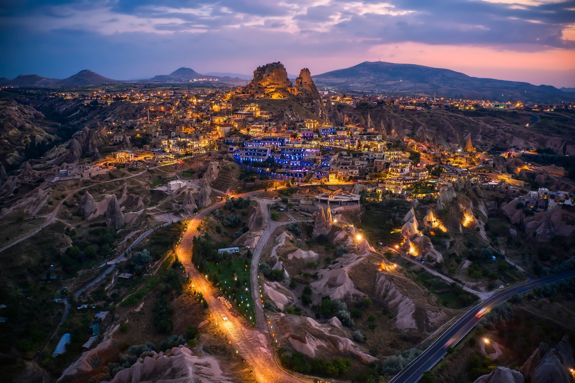 Una veduta aerea di una città circondata da montagne di notte.