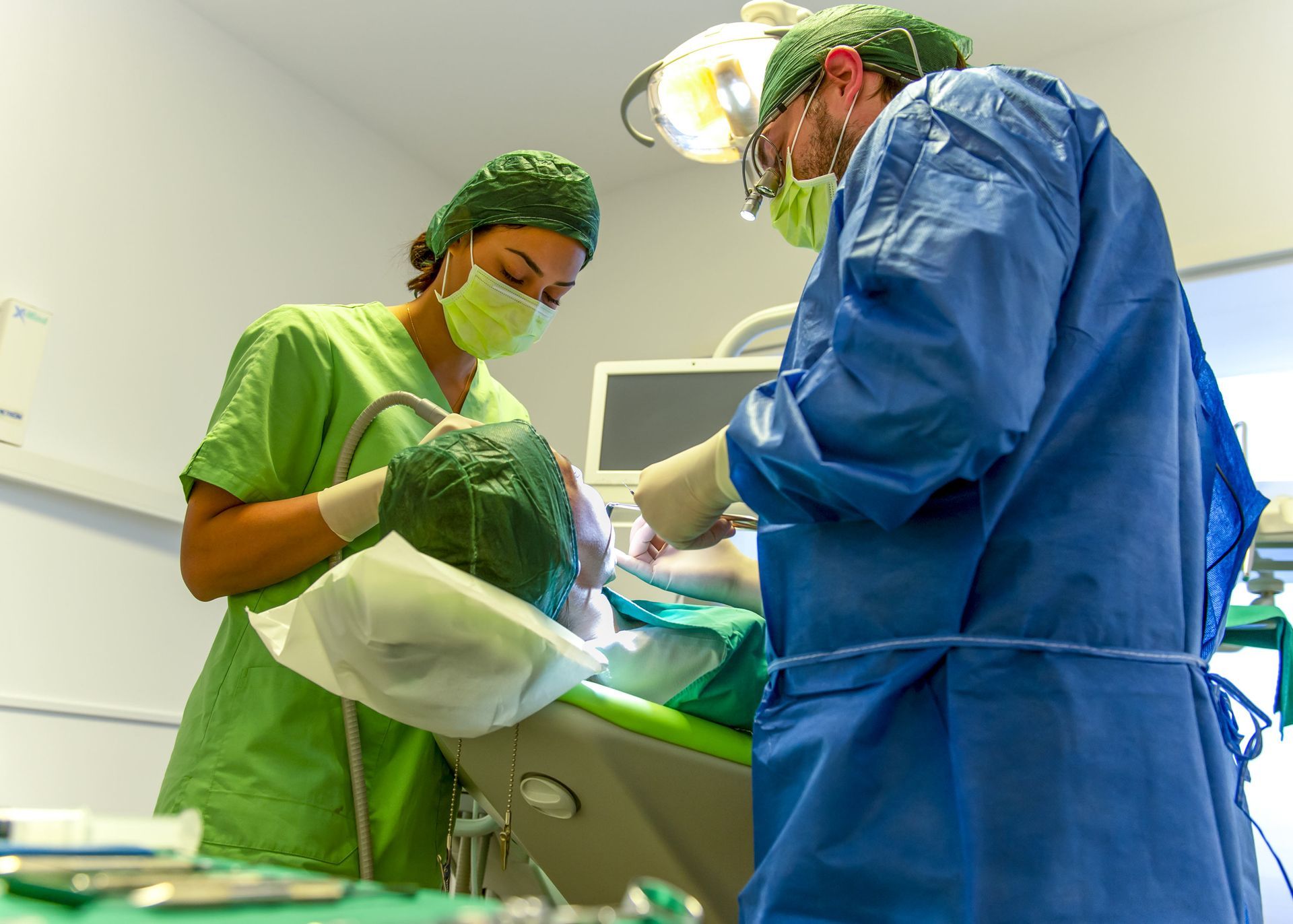 Un uomo e una donna stanno operando un paziente in una sala odontoiatrica.