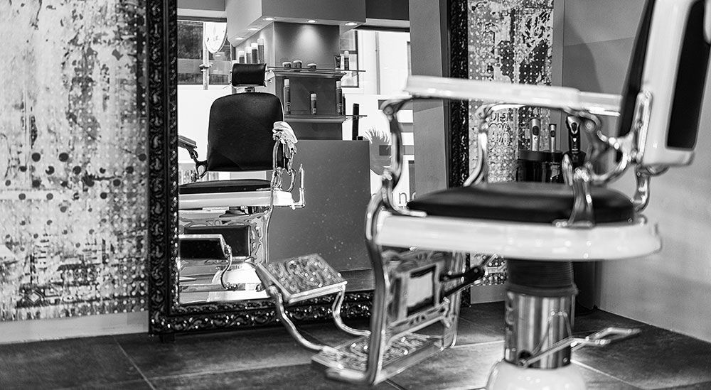 Una foto in bianco e nero di una poltrona da barbiere in un negozio di barbiere.