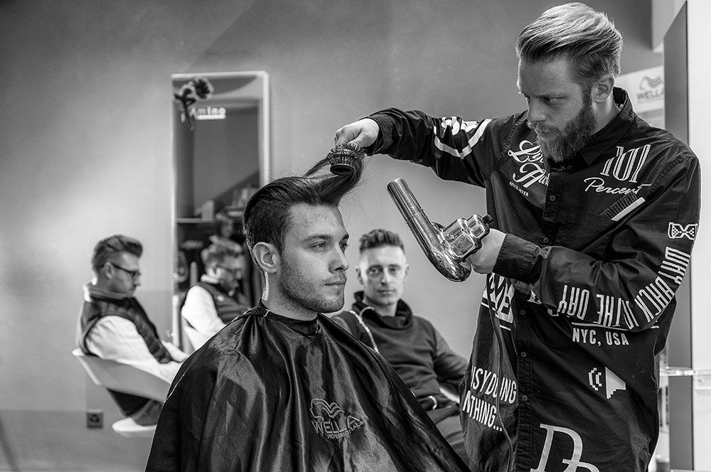 Un uomo si fa tagliare i capelli da un barbiere in una foto in bianco e nero.