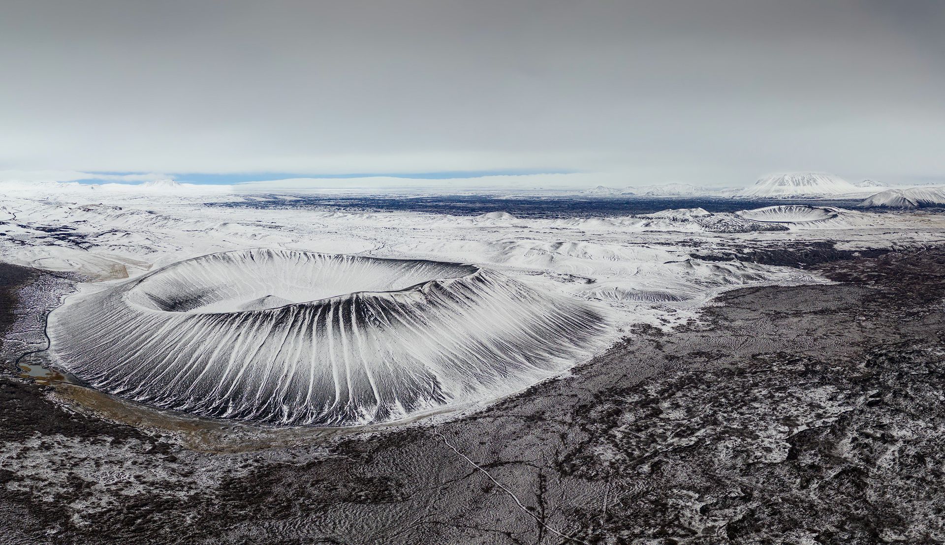 Una veduta aerea di un grande cratere nel mezzo di una montagna innevata.