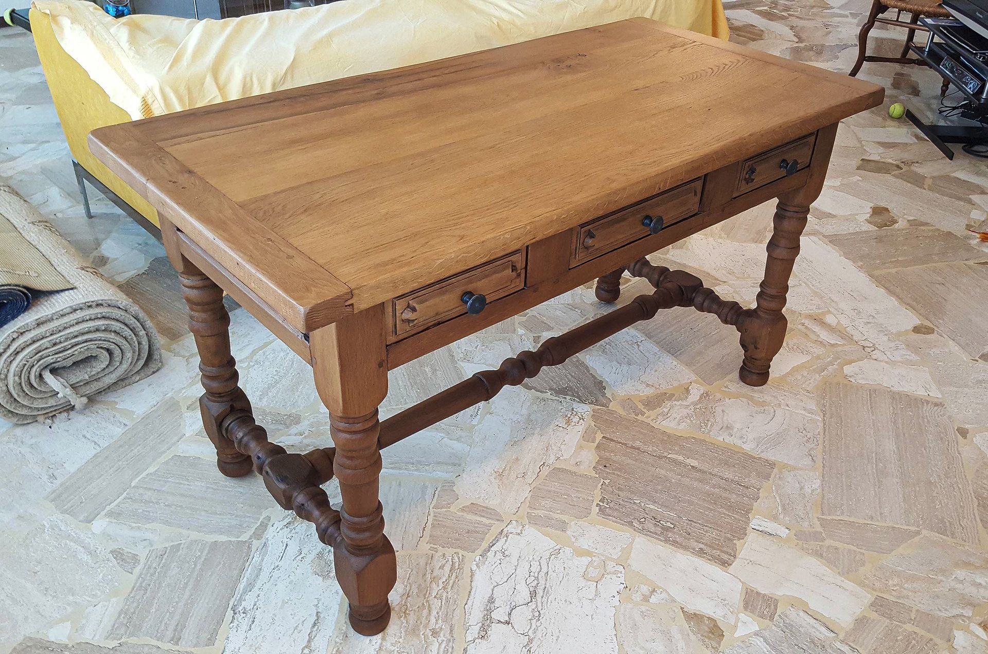 Un tavolo di legno è appoggiato su un pavimento di pietra accanto a un divano giallo.