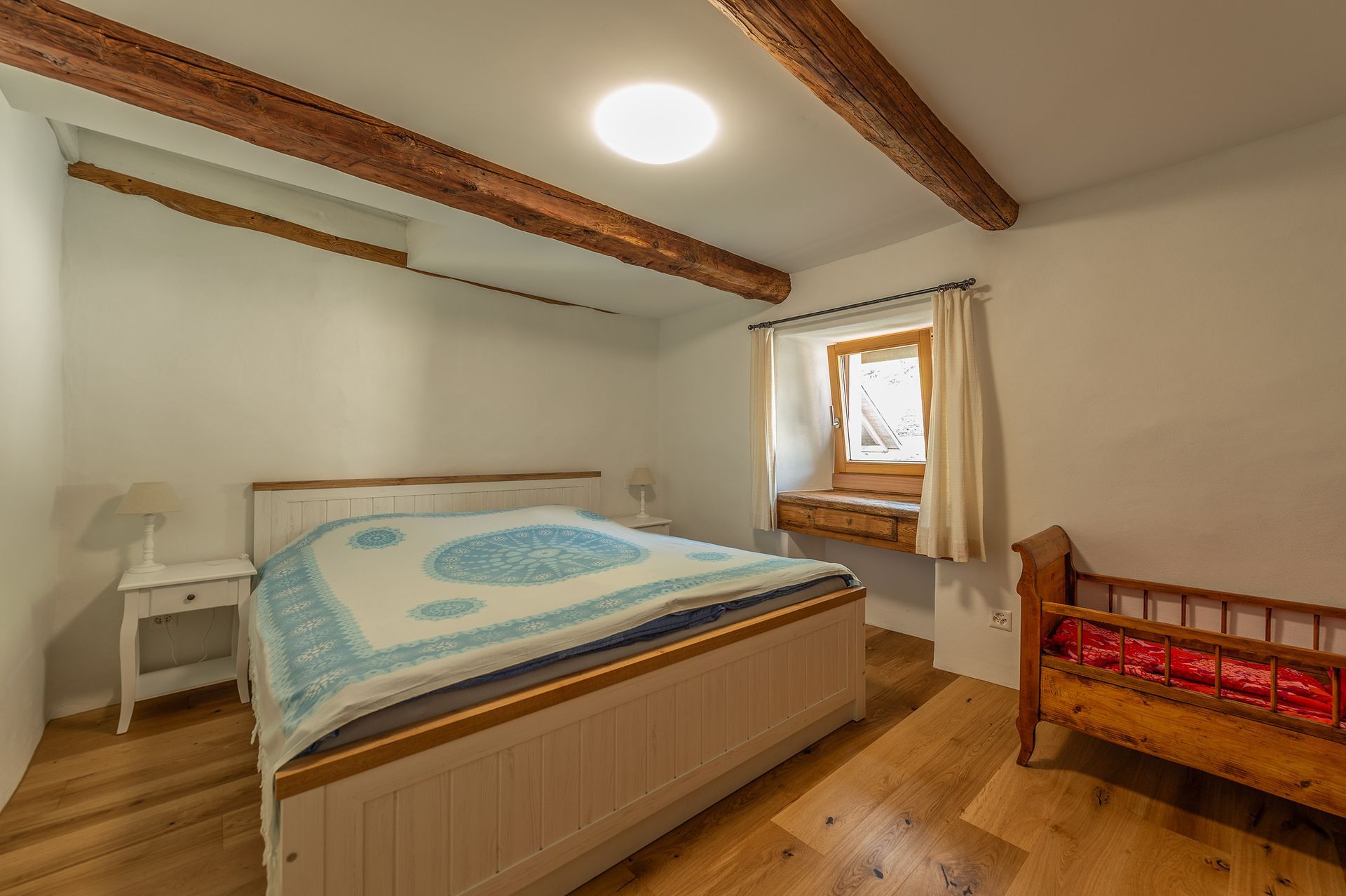 Una camera con letto, comodino, culla e finestra.