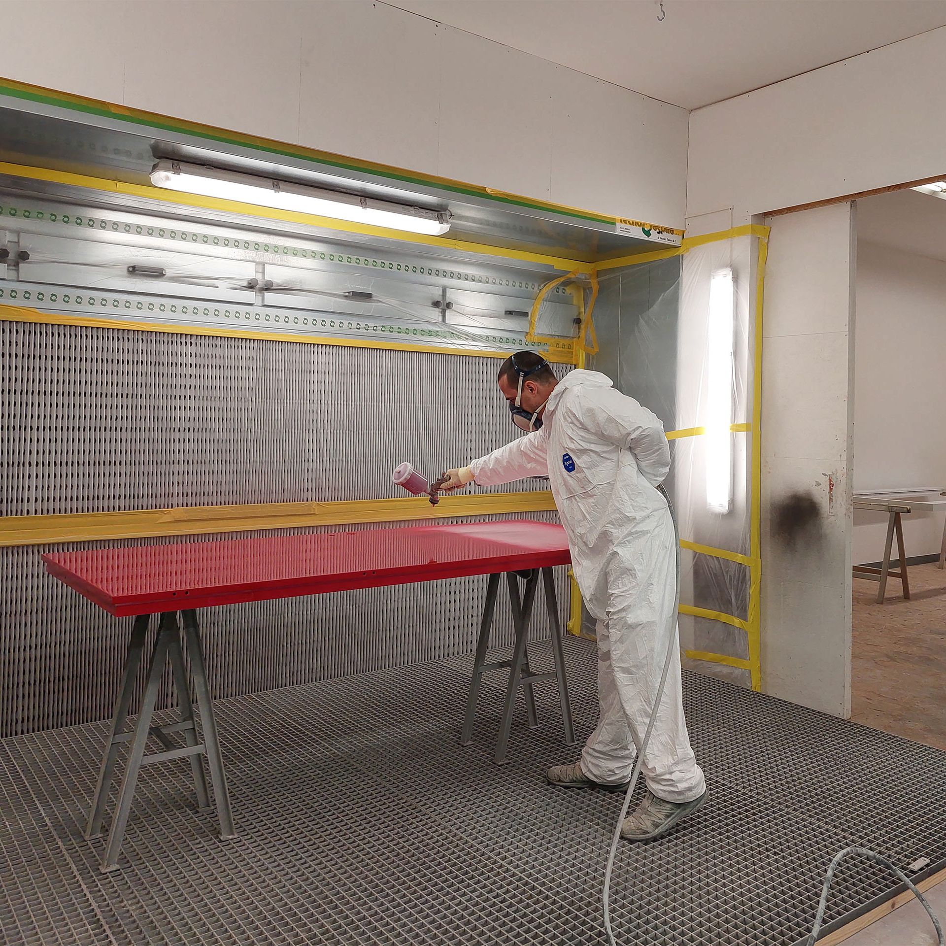 Un uomo vestito di bianco sta dipingendo un tavolo rosso.