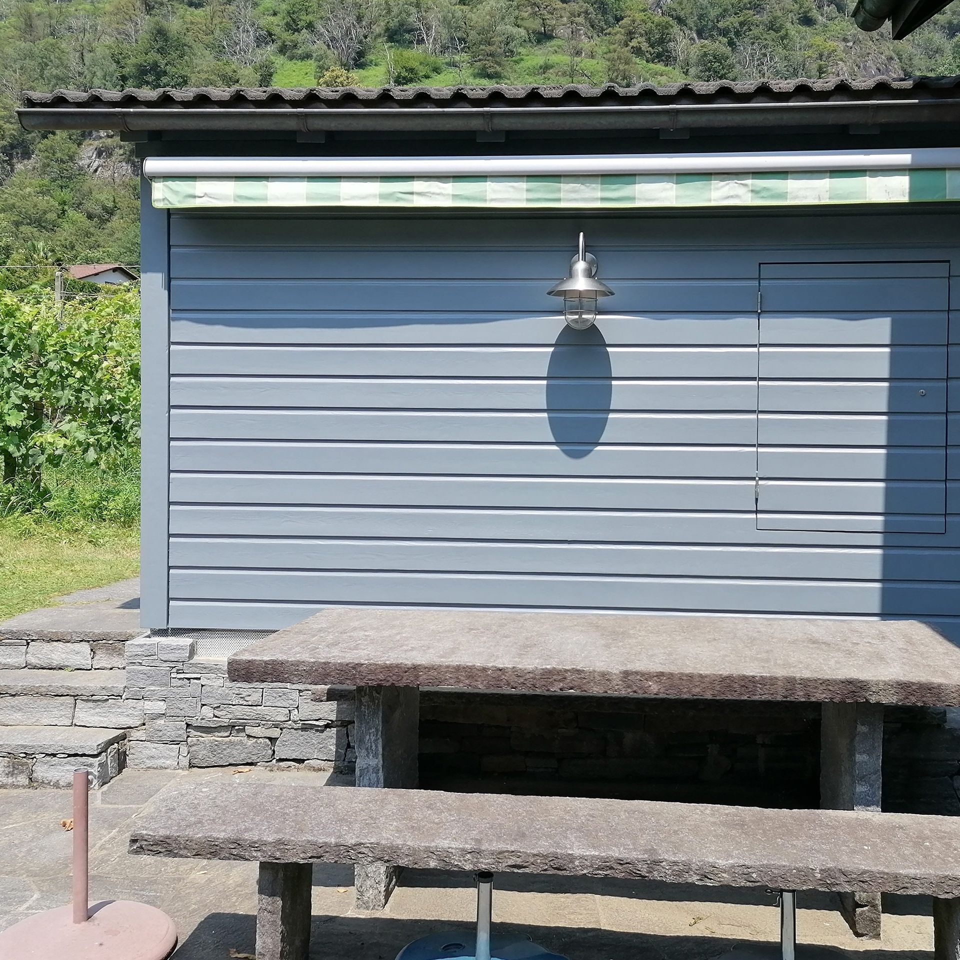 Una tettoia grigia con davanti un tavolo da picnic