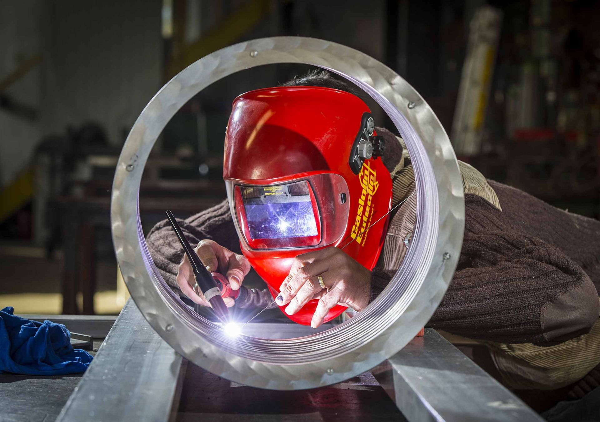 Un uomo che indossa un casco da saldatura sta saldando un tubo metallico.