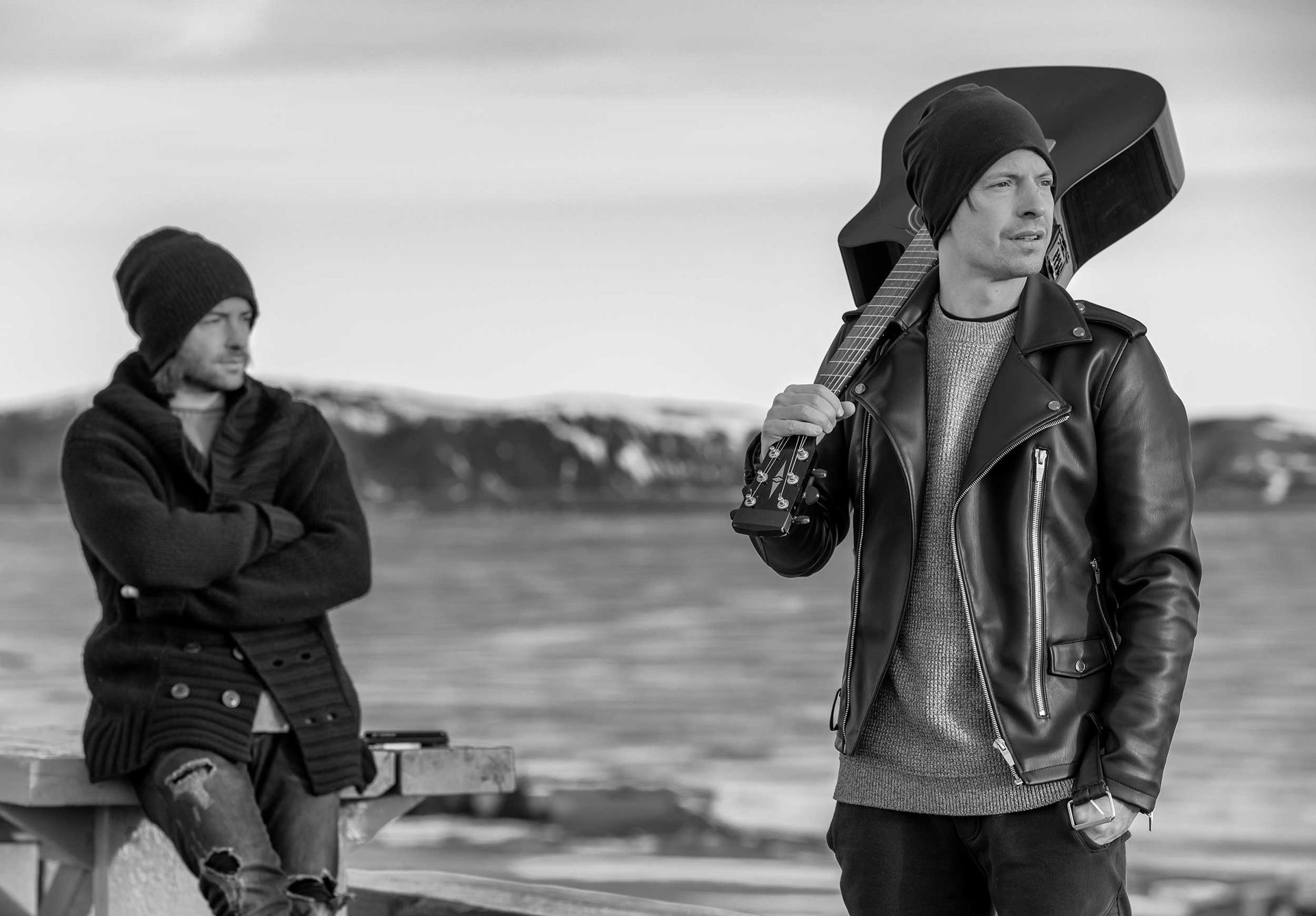 Due uomini sono uno accanto all'altro in una foto in bianco e nero. uno degli uomini tiene in mano una chitarra.